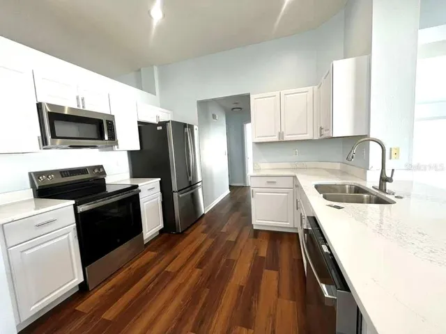 a kitchen with a sink a microwave a refrigerator and cabinets