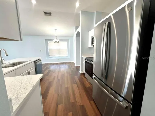 a view of a kitchen with wooden floor and electronic appliances
