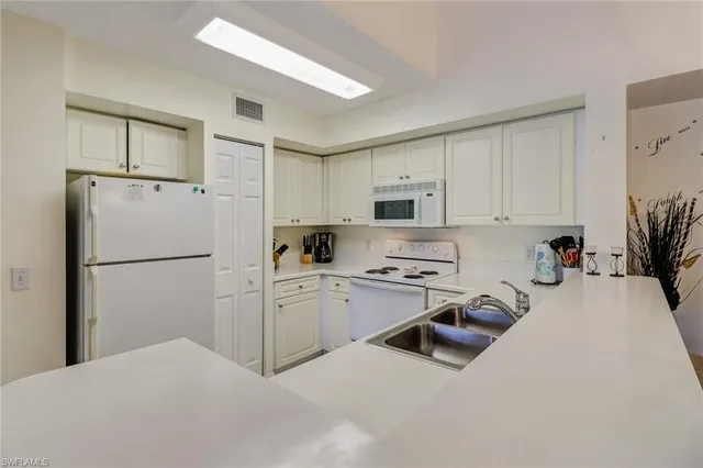 a kitchen with white cabinets and white appliances