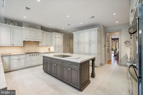 a kitchen with stainless steel appliances granite countertop a dining table chairs and stove top oven