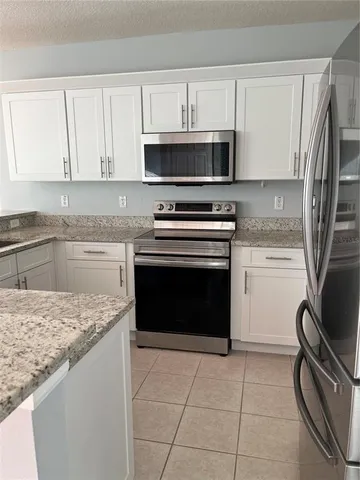 a kitchen with granite countertop a stove sink and cabinets