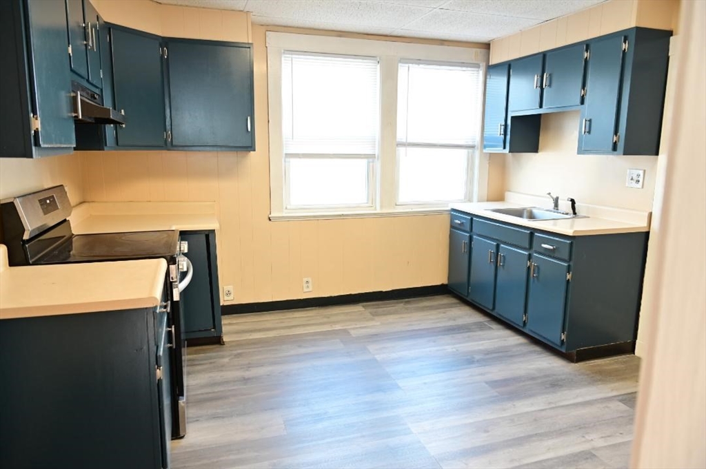 90 Elmer Road, Unit 2 Boston, MA 02124 - Photo 11 of 12 a kitchen with stainless steel appliances granite countertop a sink cabinets and wooden floor