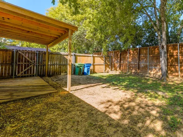 a view of backyard with wooden fence and a large tree