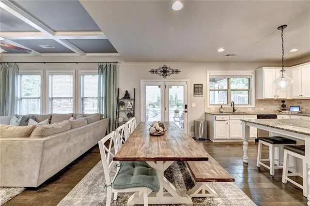 a dining room with stainless steel appliances kitchen island granite countertop a table chairs and a refrigerator