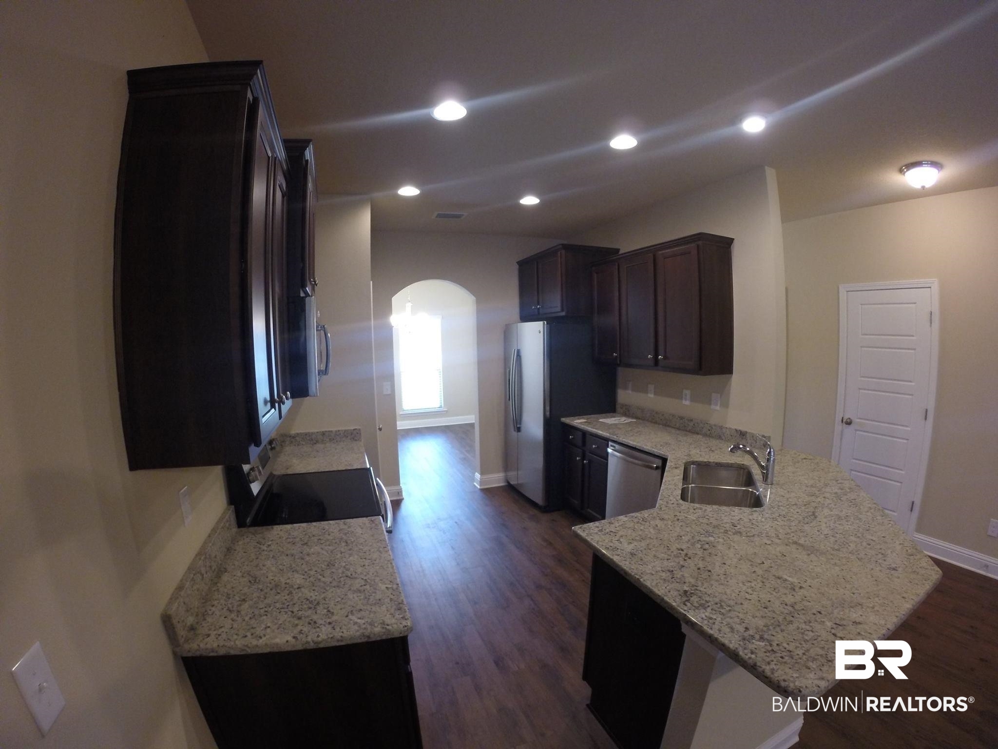 2996 Notsram Court Mobile, AL 36695 - Photo 5 of 16 Kitchen with a sink, appliances with stainless steel finishes, baseboards, dark wood-style flooring, and a peninsula