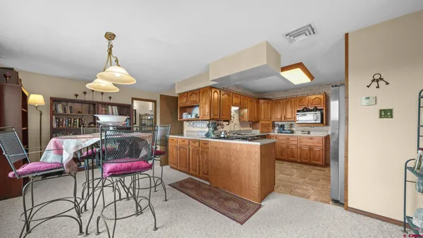 a kitchen with stainless steel appliances kitchen island granite countertop a dining table chairs and a refrigerator