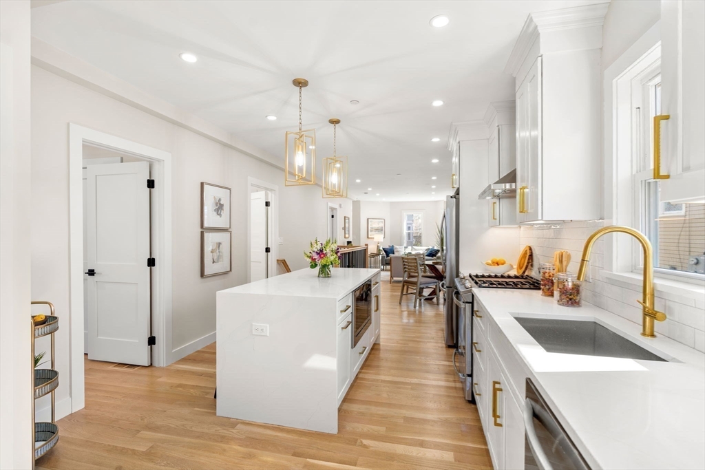 10 Marion Road, Unit 1 Belmont, MA 02478 - Photo 5 of 26 a large kitchen with stainless steel appliances a stove a sink a refrigerator and a dining table with wooden floor
