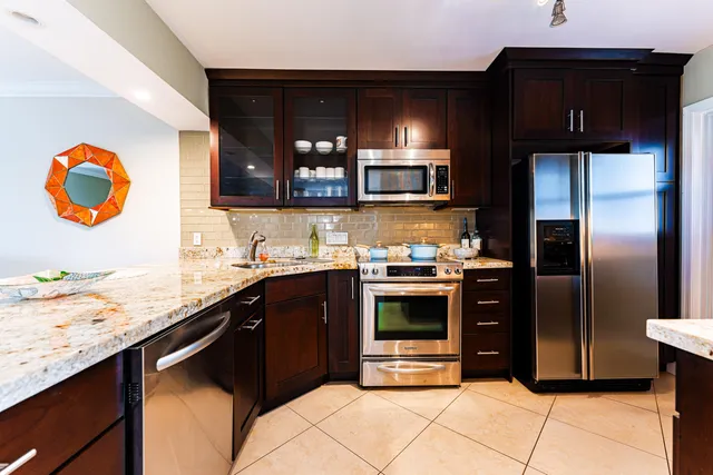 a kitchen with granite countertop a sink cabinets and stainless steel appliances