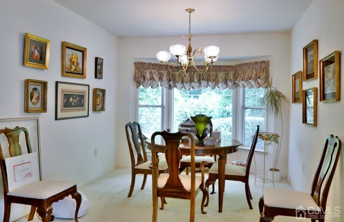 171 Concordia Circle, Unit C Monroe Township, NJ 08831 - Photo 3 of 13 a view of a dining room with furniture a chandelier window and wooden floor