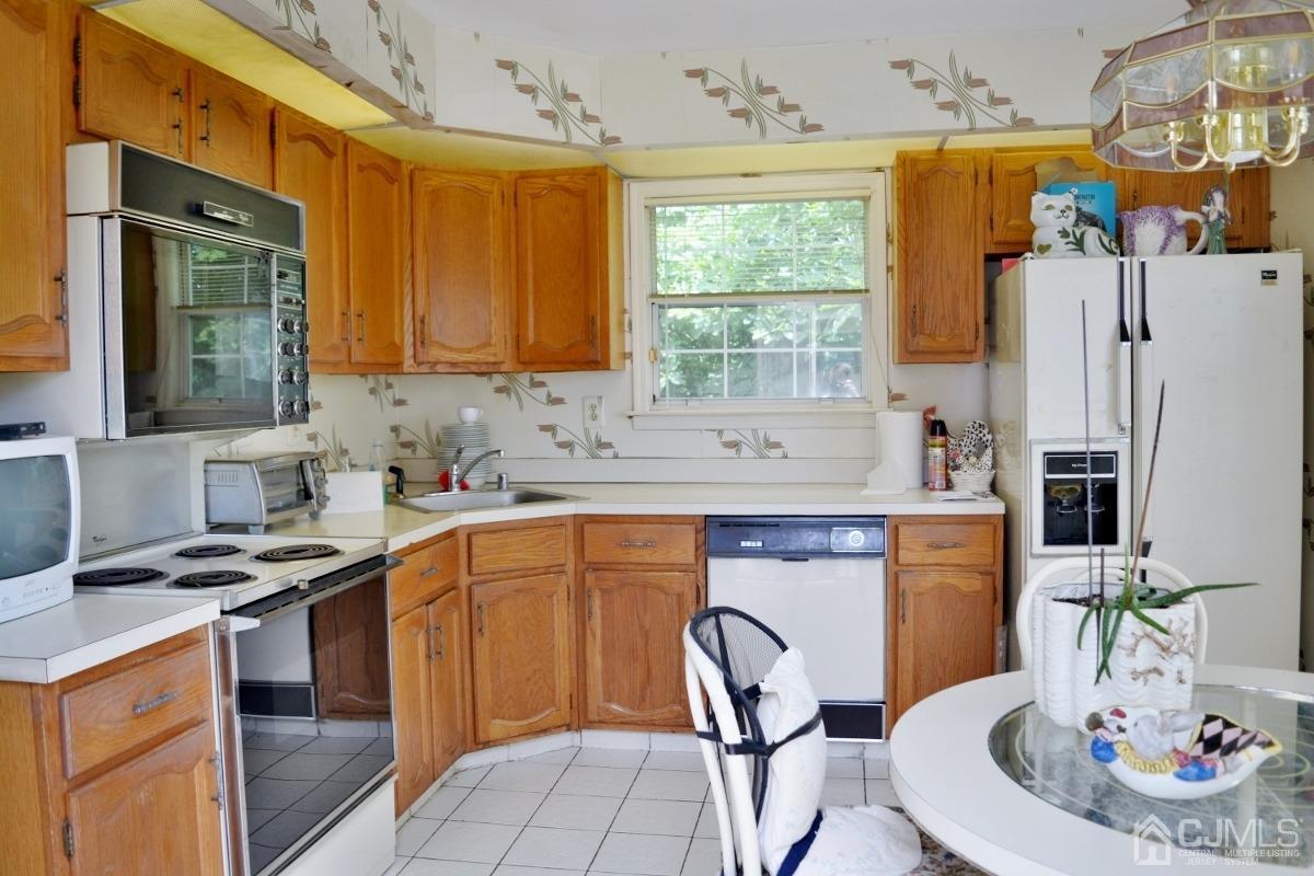 171 Concordia Circle, Unit C Monroe Township, NJ 08831 - Photo 5 of 13 a kitchen with stainless steel appliances a stove a sink a refrigerator wooden floor and a dining table with wooden floor