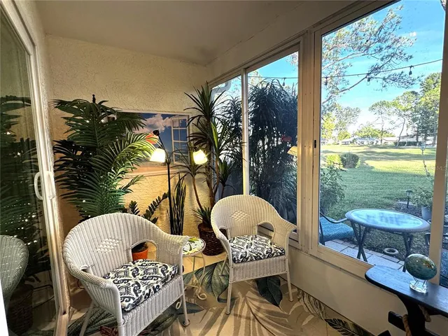 a living room with chairs and a floor to ceiling window