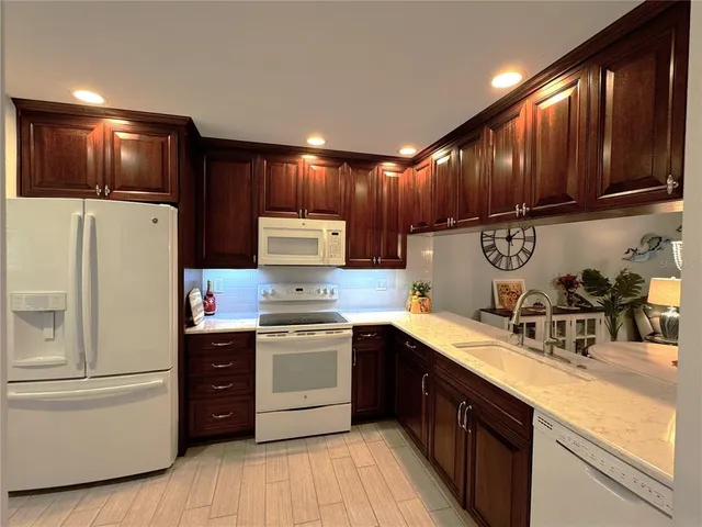 a kitchen with granite countertop wooden cabinets and white appliances