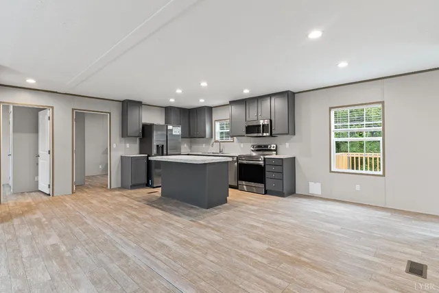 a large kitchen with stainless steel appliances granite countertop a stove a sink dishwasher a refrigerator and white cabinets with wooden floor