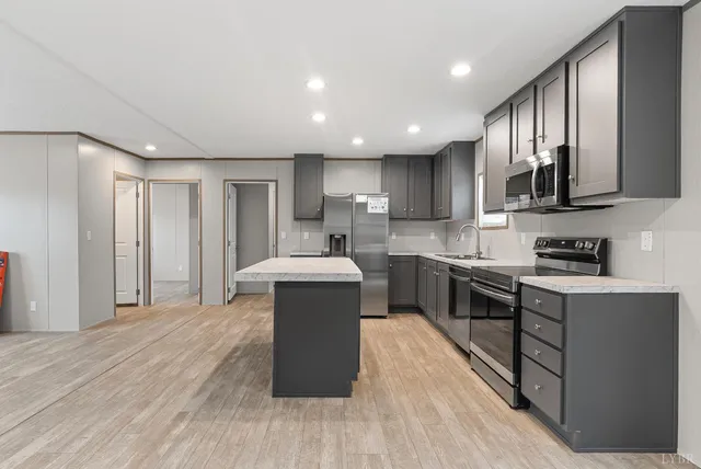 a kitchen with stainless steel appliances granite countertop a stove a sink dishwasher and a refrigerator with wooden floor