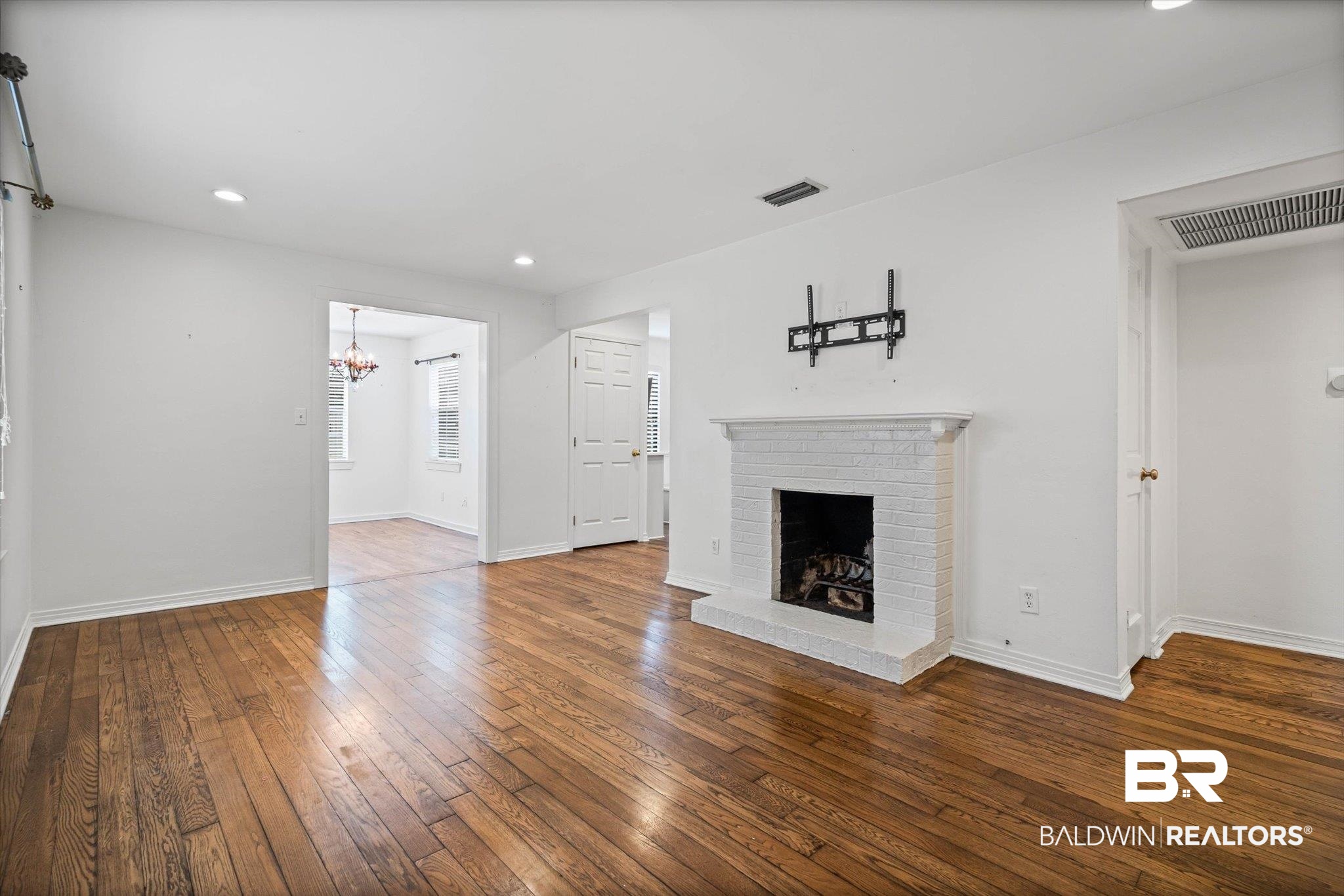 11 York Place Mobile, AL 36608 - Photo 2 of 24 Unfurnished living room featuring recessed lighting, a brick fireplace, dark wood-style floors, and a chandelier