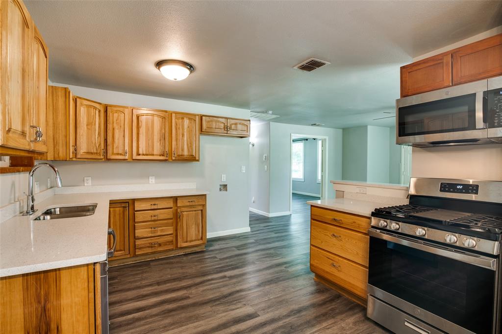 606 West High Street Terrell, TX 75160 - Photo 11 of 28 a kitchen with stainless steel appliances kitchen island granite countertop a stove and a sink