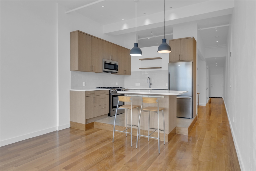 70-72 Northampton Street, Unit 502 Boston, MA 02118 - Photo 2 of 19 a kitchen with stainless steel appliances kitchen island granite countertop a stove a sink and a refrigerator