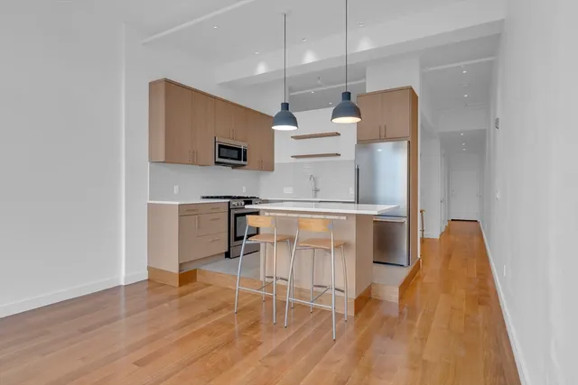 a kitchen with stainless steel appliances a dining table chairs and microwave