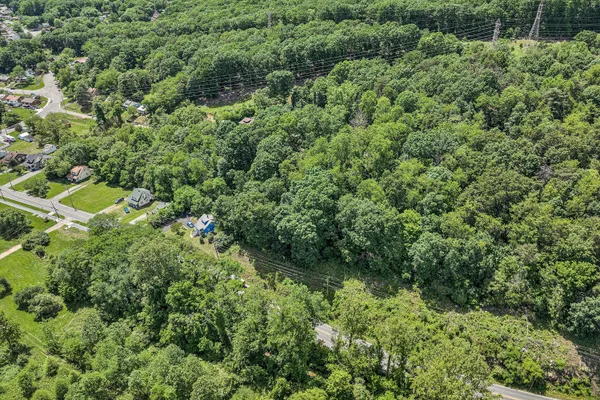 an aerial view of residential house with outdoor space and trees all around