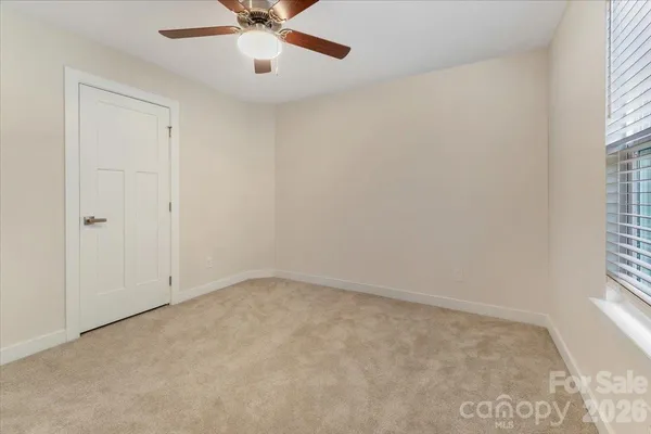 an empty room with a window and a fan