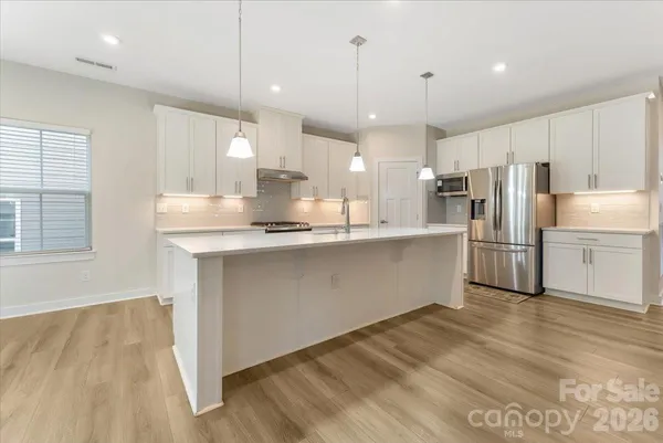 a kitchen with kitchen island a sink a center island stainless steel appliances and a window