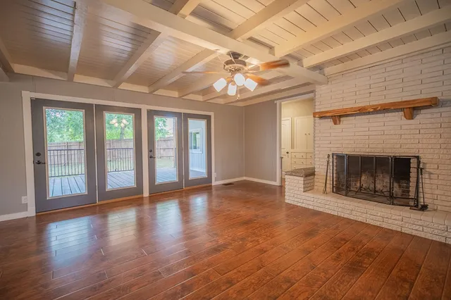 a view of an empty room with wooden floor fireplace and a window