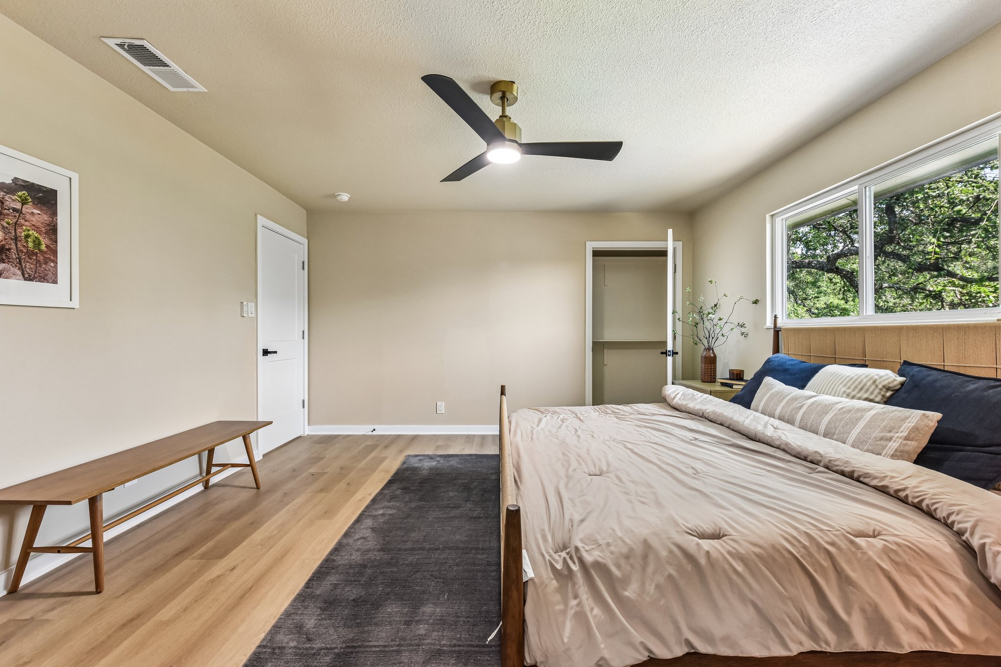 7523 Glenhill Road Austin, TX 78752 - Photo 19 of 38 Natural light floods this inviting bedroom, highlighting the smooth plank flooring and contemporary ceiling fan.