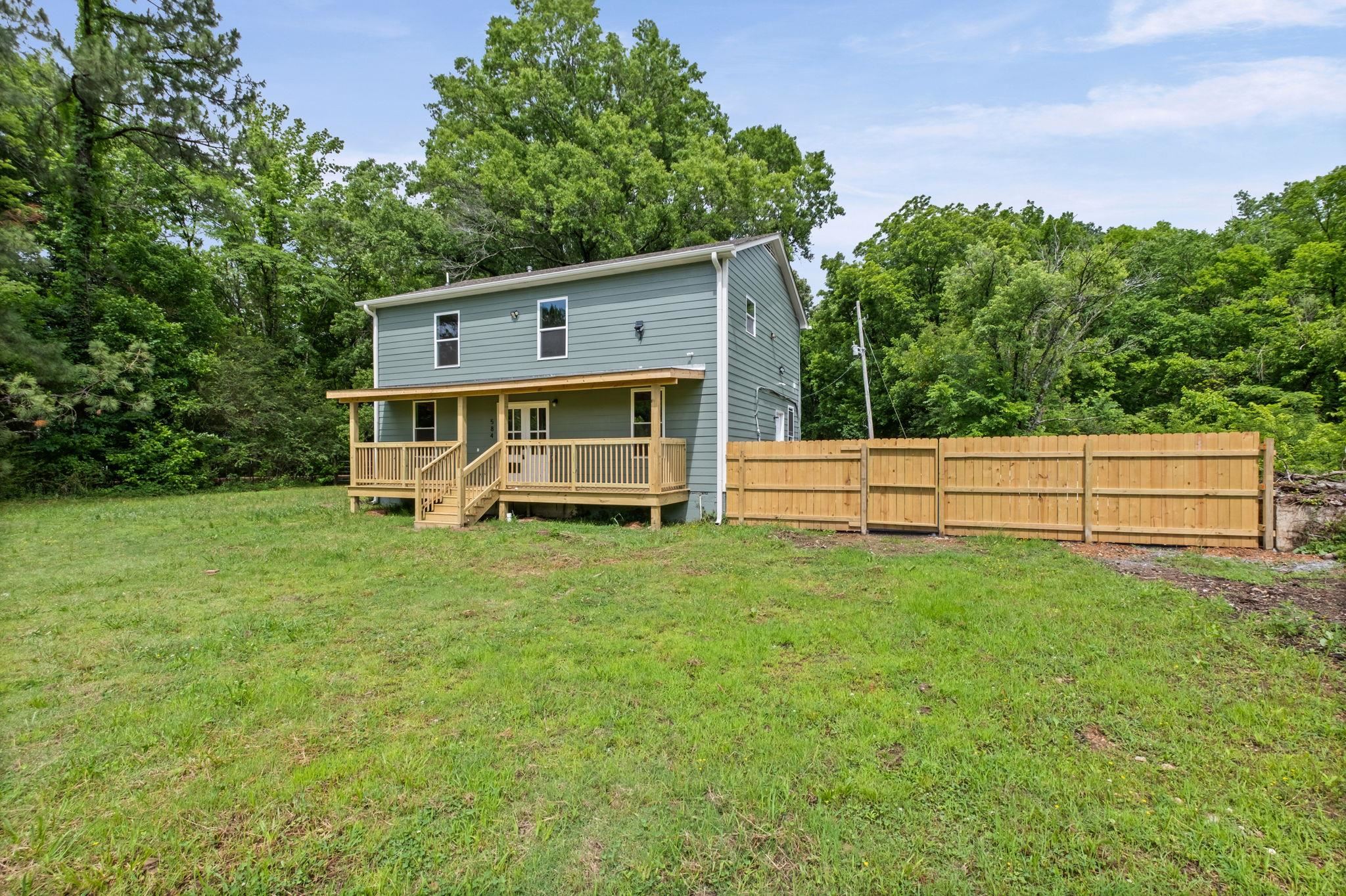 5843 Stewart Road Lakeland, TN 38002 - Photo 3 of 26 Two-story residence featuring light blue siding, a covered front porch with natural wood railings, and a new privacy fence
