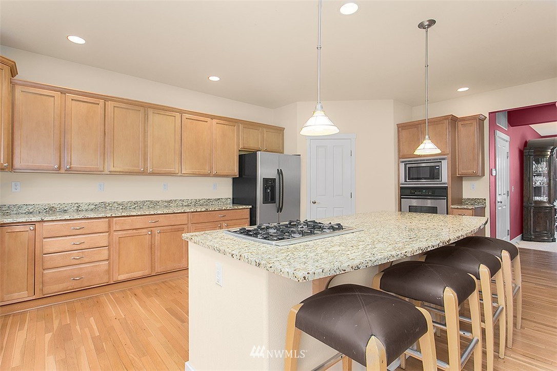 21913 42 Avenue Southeast Bothell, WA 98021 - Photo 3 of 24 a kitchen with kitchen island granite countertop a stove a sink a refrigerator and white cabinets with wooden floor