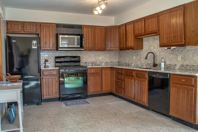 a kitchen with stainless steel appliances granite countertop wooden cabinets a stove top oven a sink and dishwasher