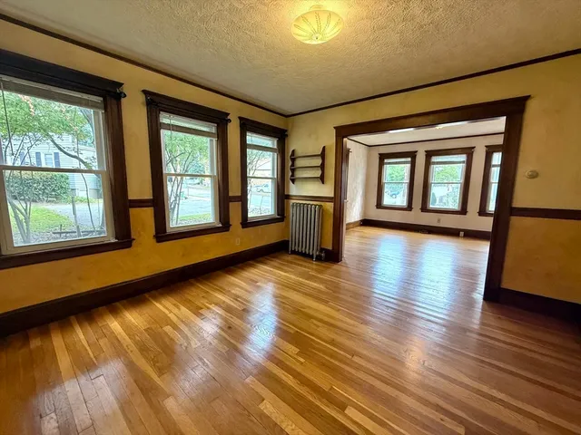 a view of an empty room with wooden floor and a window