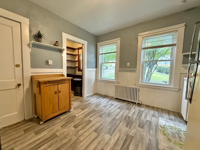 an empty room with wooden floor cabinet and windows