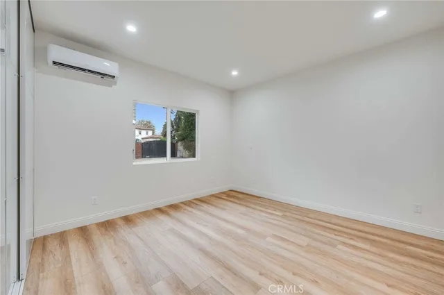 a view of empty room with window and wooden floor