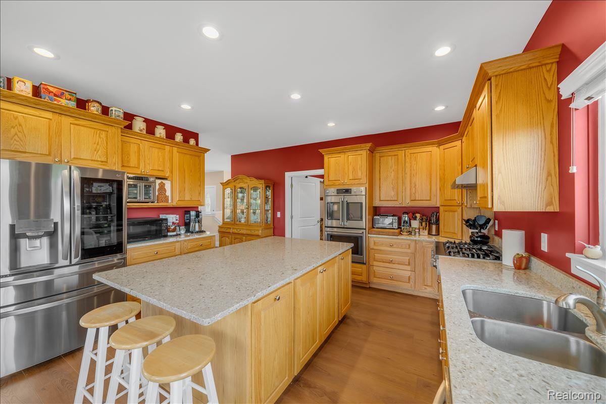 4266 McCandlish Road Grand Blanc, MI 48439 - Photo 19 of 68 Kitchen featuring light wood cabinetry with crown molding, stainless steel appliances, a center island with a light-colored countertop, and a double basin sink