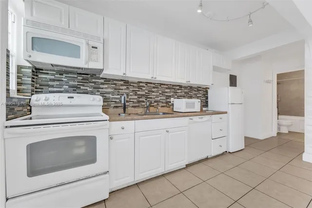 a kitchen with white cabinets and white appliances
