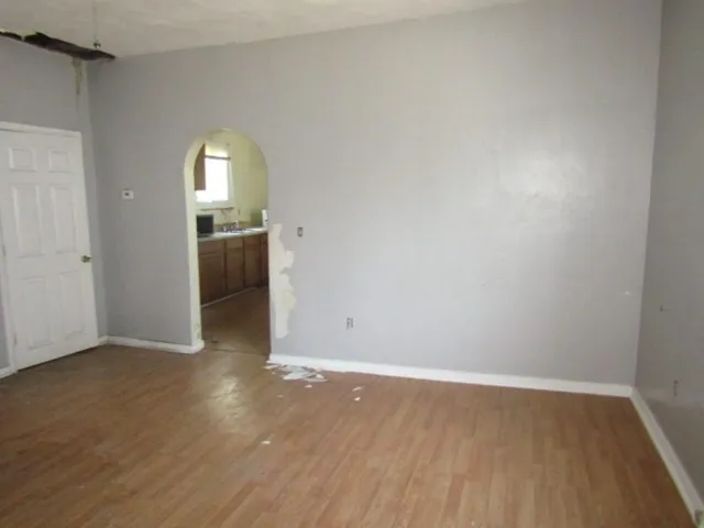 an empty room with wooden floor and mirror