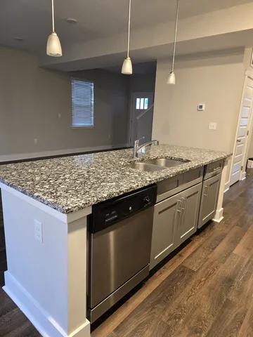 a kitchen with stainless steel appliances granite countertop wooden cabinets and a wooden floor