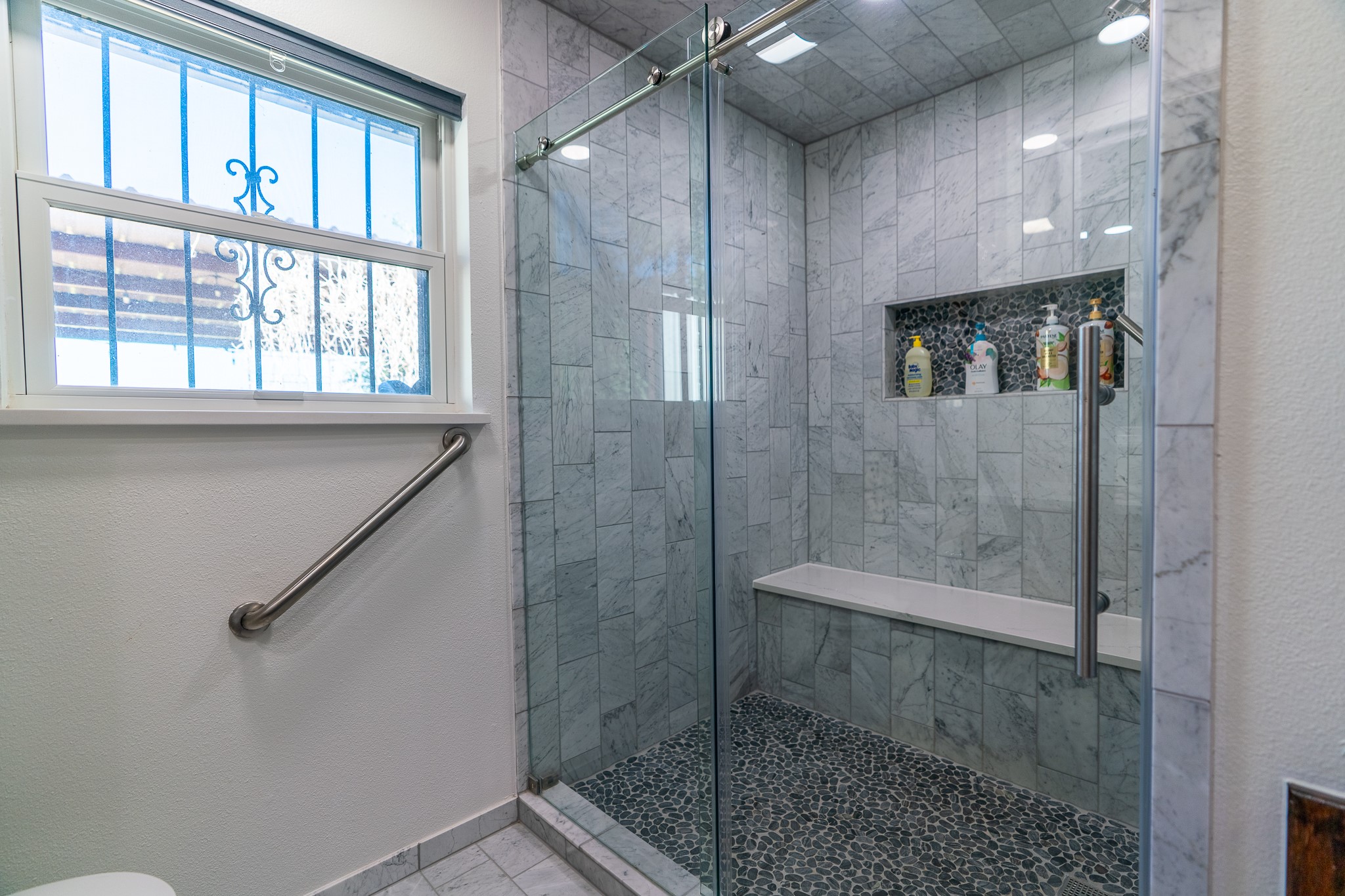 400 619th Spur Elgin, TX 78621 - Photo 29 of 40 A well-appointed shower space boasts glass enclosure, built-in shelving, and a comfortable bench for relaxation.