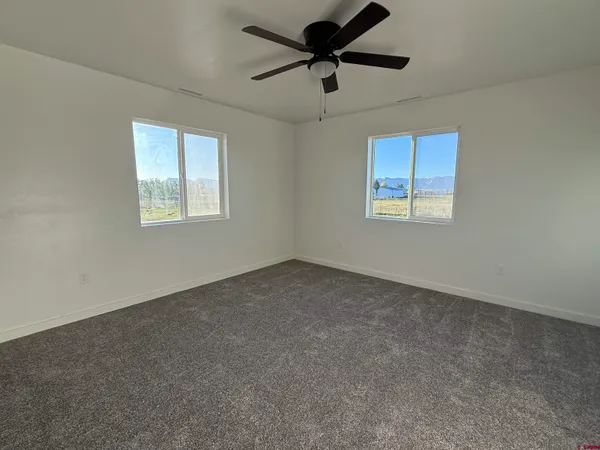 an empty room with windows and fan