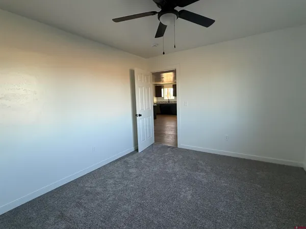 a view of a hallway with wooden floor and a bathroom