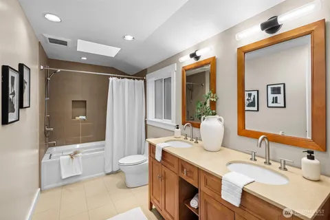 a bathroom with double vanity sinks a toilet a mirror and shower