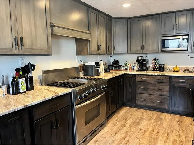 a kitchen with stainless steel appliances granite countertop a stove a sink dishwasher and cabinets with wooden floor