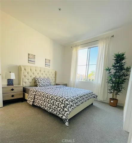 a bed sitting in a bedroom next to a window with potted plants