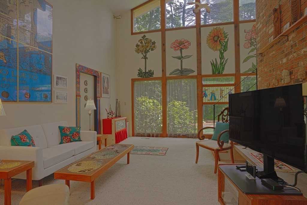 17 Juniper Lane Amherst, MA 01002 - Photo 9 of 42 a living room with furniture a flat screen tv and a floor to ceiling window