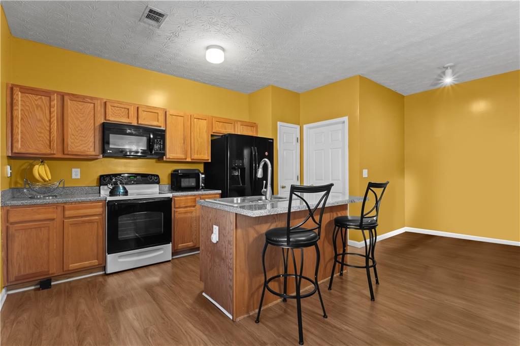 3000 Western Sunset Decatur, GA 30034 - Photo 17 of 37 a kitchen with stainless steel appliances granite countertop a stove top oven a sink dishwasher a dining table and chairs with wooden floor