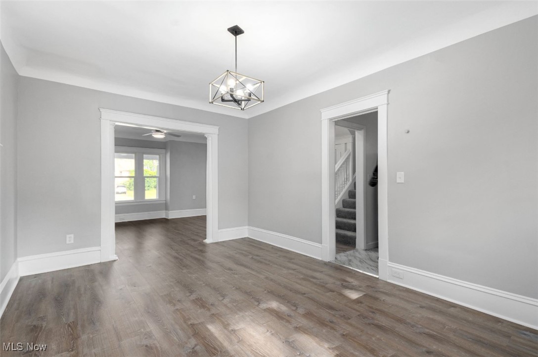 1229 Melbourne Road Cleveland, OH 44112 - Photo 8 of 22 Unfurnished dining area with a chandelier, dark wood-type flooring, stairway, and a ceiling fan