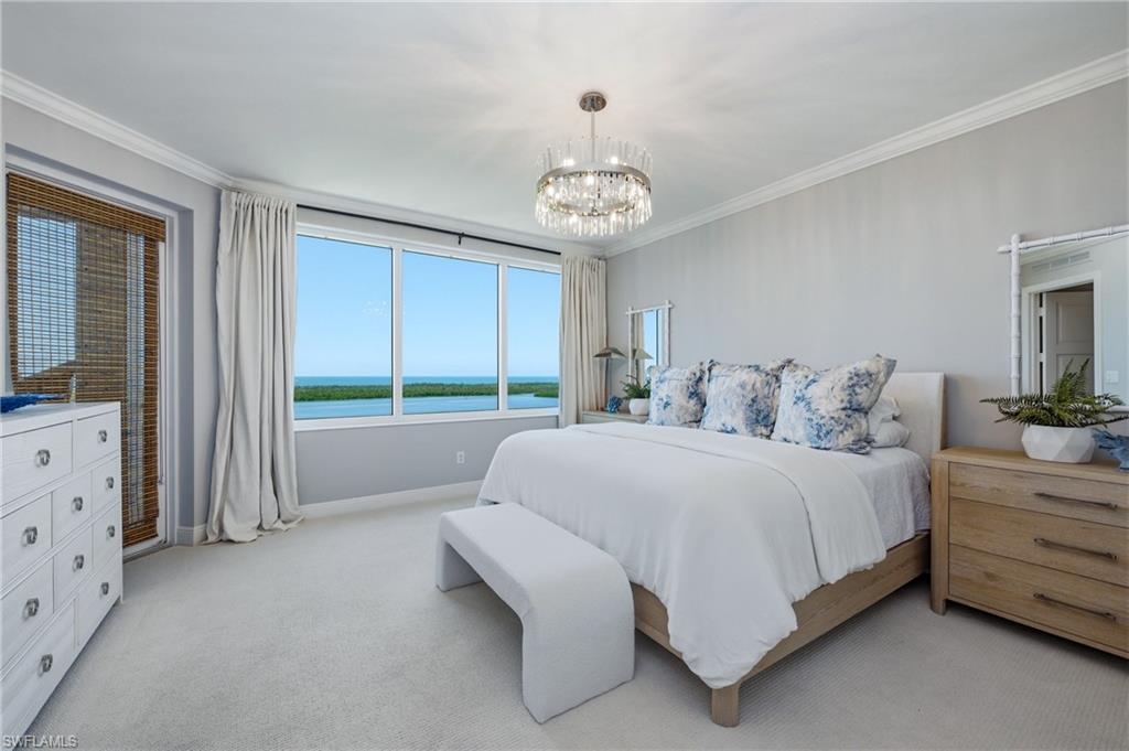 265 Indies Way, Unit 1004 Naples, FL 34110 - Photo 14 of 34 a spacious bedroom with a bed chandelier and window