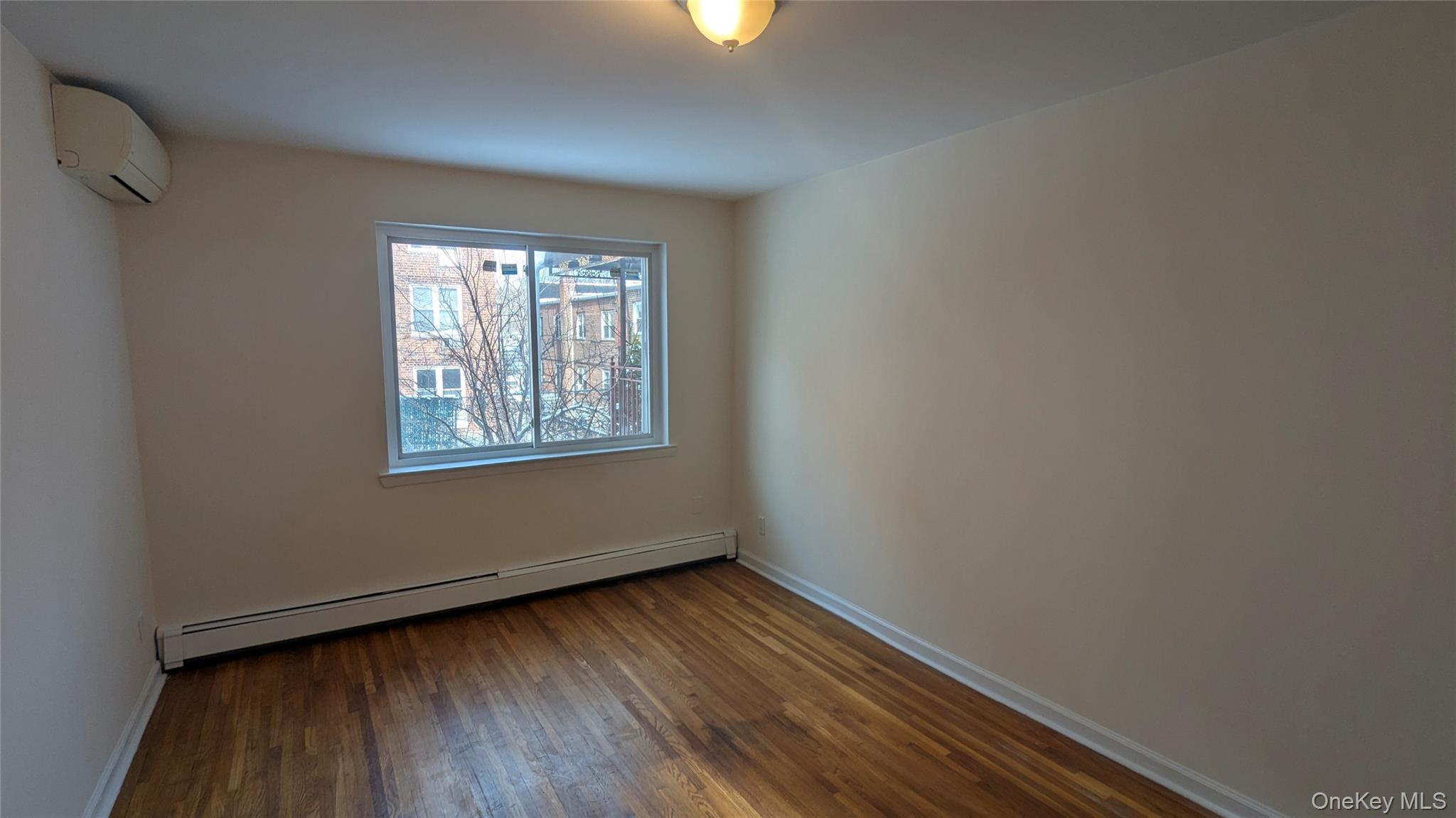99-47 62nd Road Queens, NY 11374 - Photo 16 of 21 Empty room with a baseboard radiator, dark wood-style flooring, and an AC wall unit
