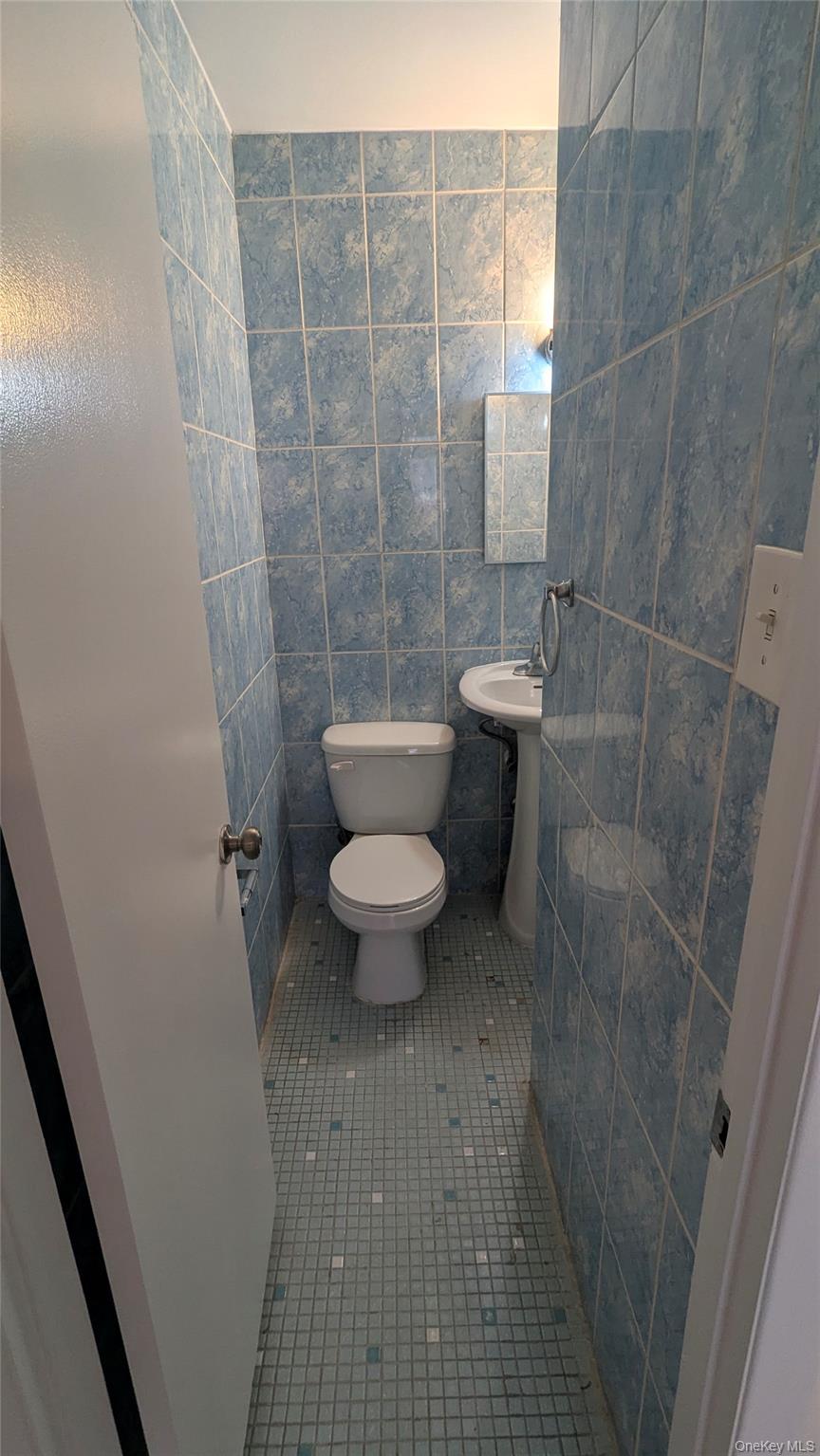99-47 62nd Road Queens, NY 11374 - Photo 18 of 21 Half bath with tile patterned floors and tile walls