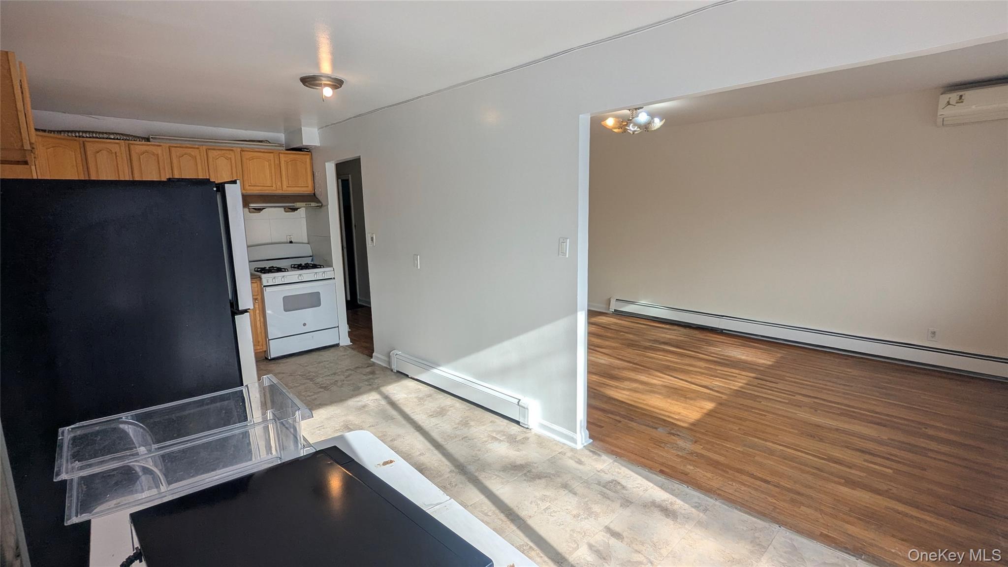 99-47 62nd Road Queens, NY 11374 - Photo 8 of 21 Kitchen with white range with gas stovetop, a baseboard radiator, freestanding refrigerator, and light wood-style floors